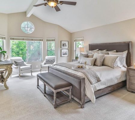 A spacious bedroom featuring a bed, dresser, and a ceiling fan overhead.