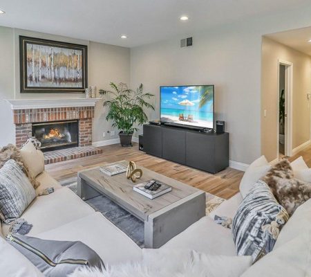 A cozy living room featuring couches, a fireplace, and a television, creating a warm and inviting atmosphere.