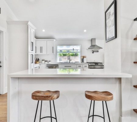A modern kitchen featuring two stools beside a sleek white counter.