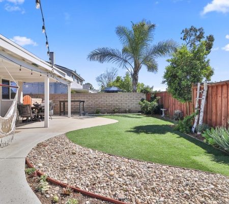 A serene backyard featuring a hammock strung between trees and a cozy patio area for relaxation and outdoor gatherings.