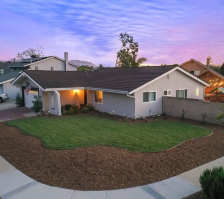 A house with a well-maintained lawn and a paved driveway leading up to the entrance.